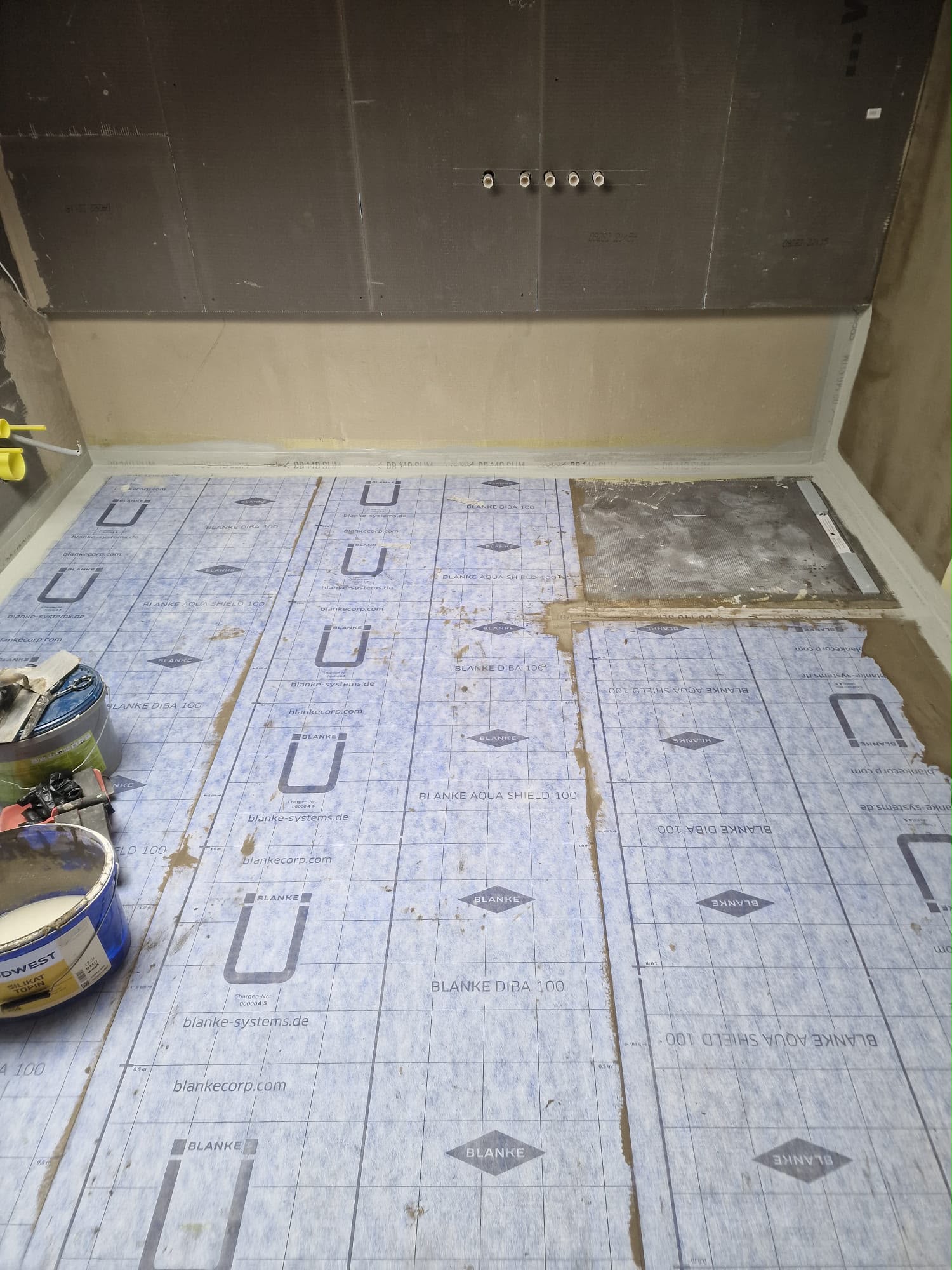 Vorarbeiten & Unterkonstruktion: Duschbereich mit Bauplatten an der Wand und vorbereitetem Boden