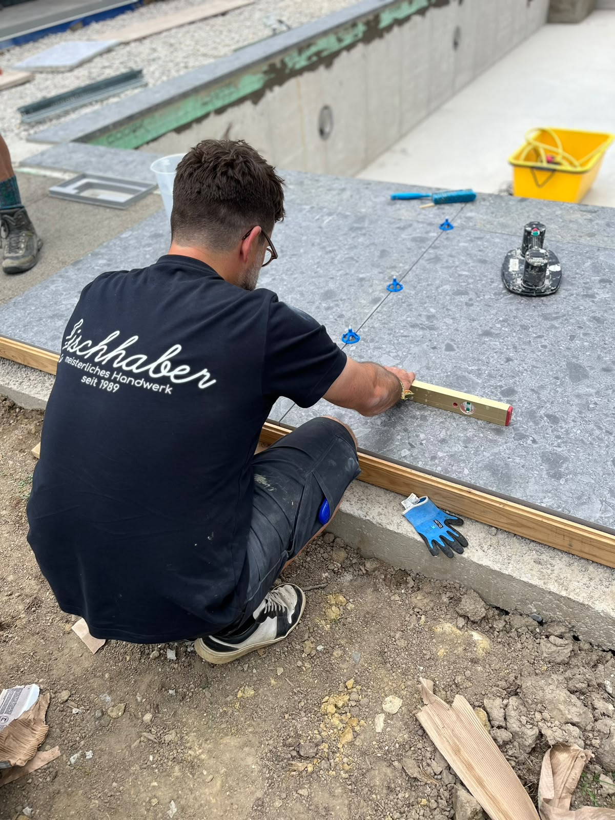 Fliesenleger von Fliesen Fischhaber beim Ausrichten großformatiger Terrassenplatten