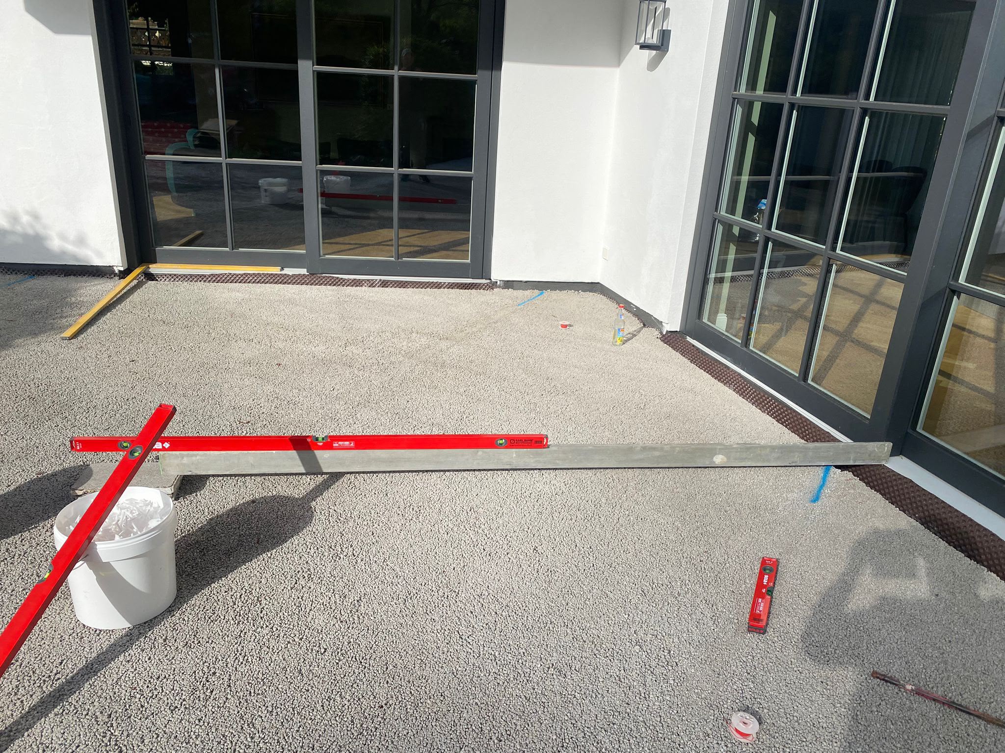 Vorbereiteter Bodenaufbau mit Schüttung und Wasserwaage vor einer Glasfront